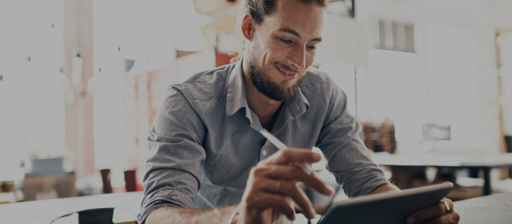 Ein Gründer sitzt vor einem Tablet und recherchiert, welche Gewerbeversicherung er für sein Startup benötigt.